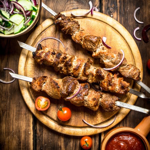 Runder Kebab Spiesjes 10 kilo a 120 gram 2 Kebab with fresh salad of cucumbers and onions. On wooden background.
