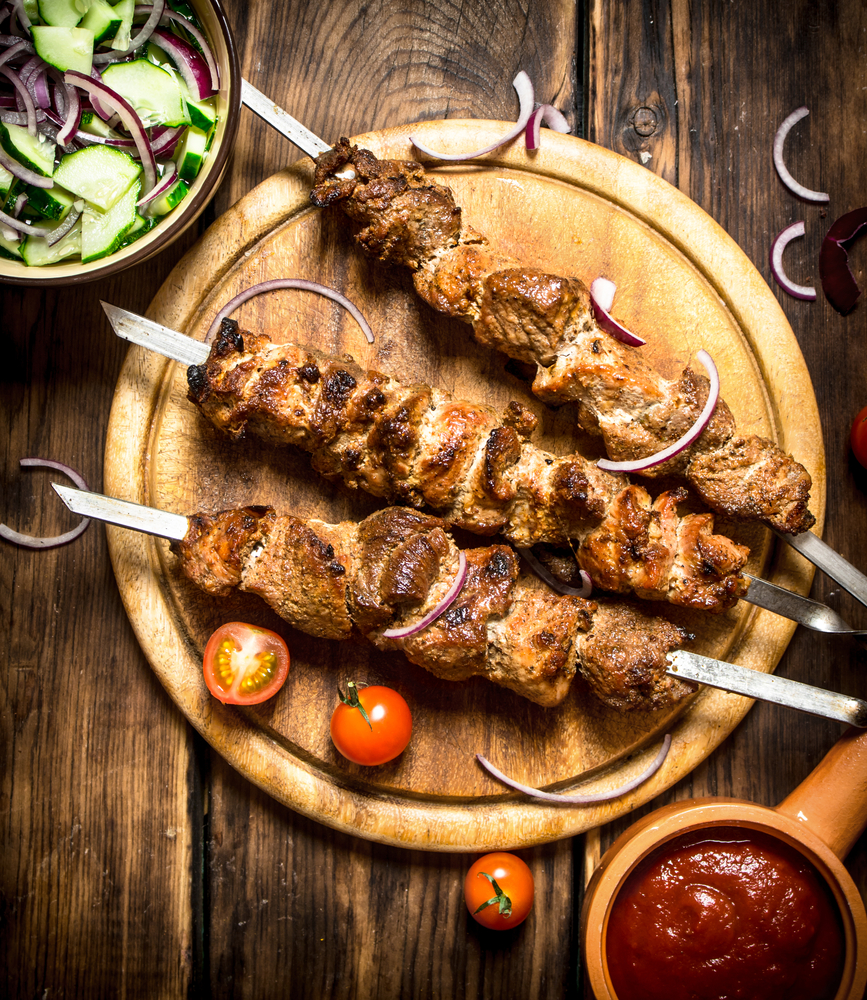 Kebab with fresh salad of cucumbers and onions. On wooden background.