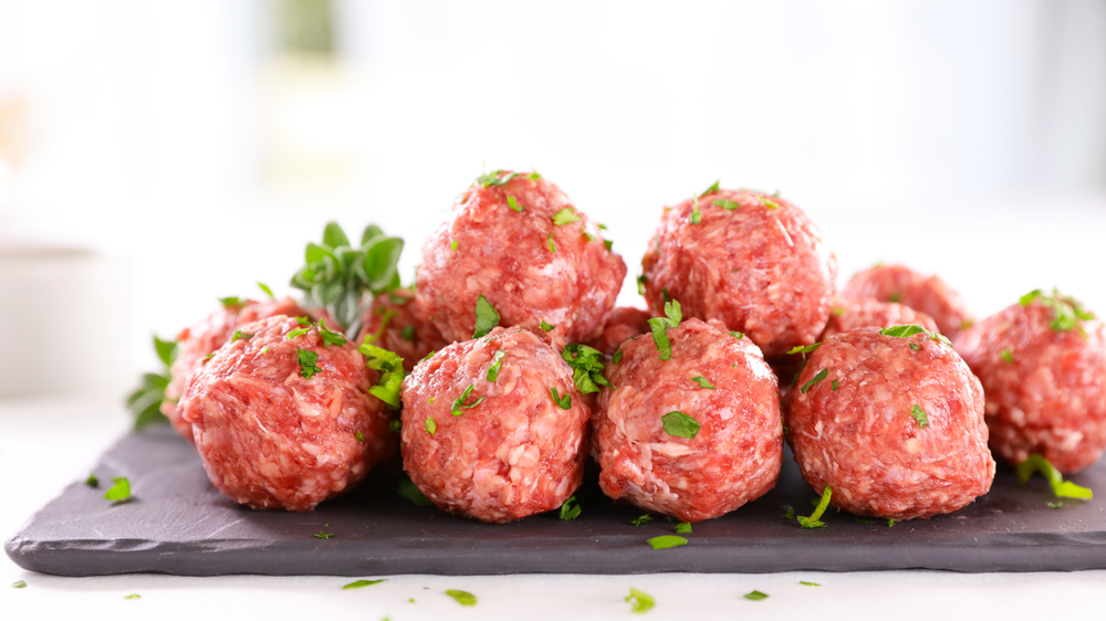 raw meatballs and herbs on board